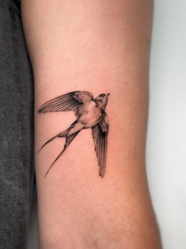 Tatuaje de un pájaro volando en el brazo.